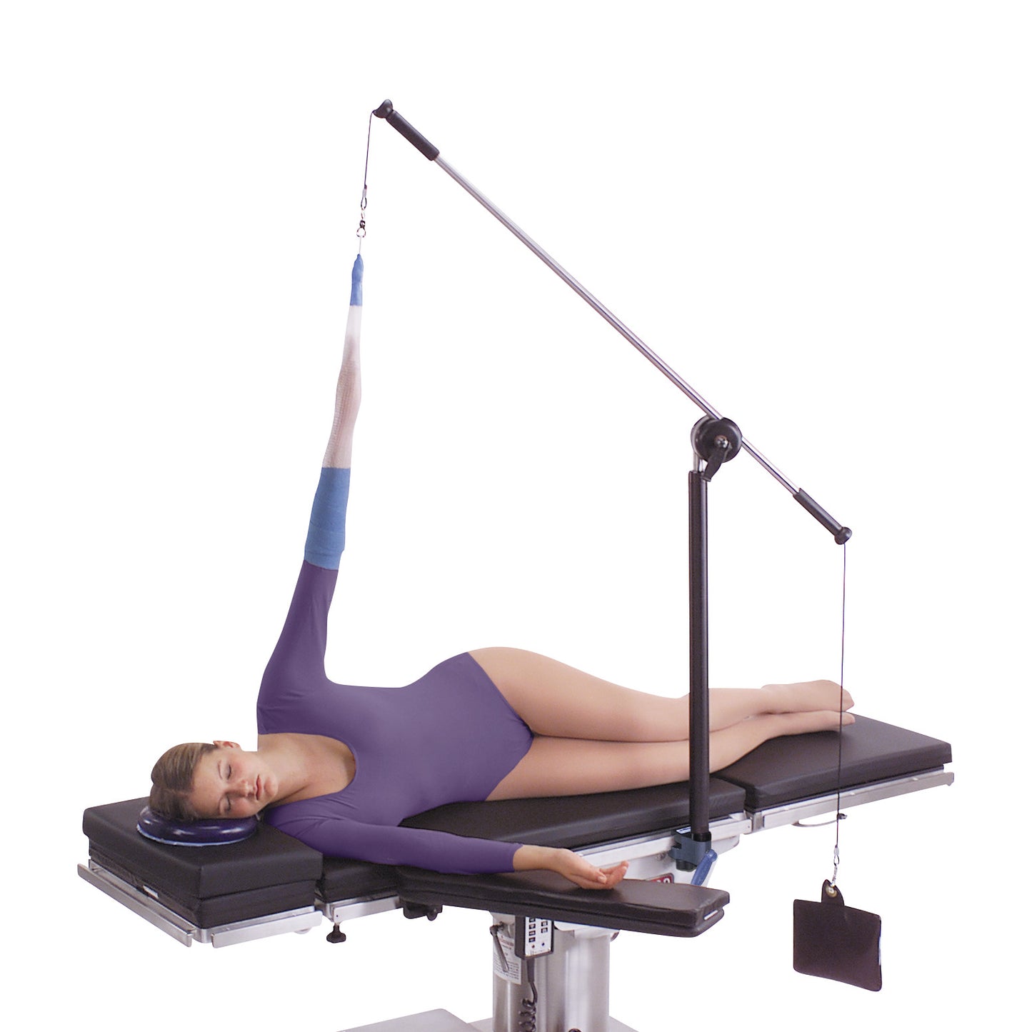 A person lies on a table with their arm secured in an elevated position using the Allen Arm Traction Device wearing a purple outfit.