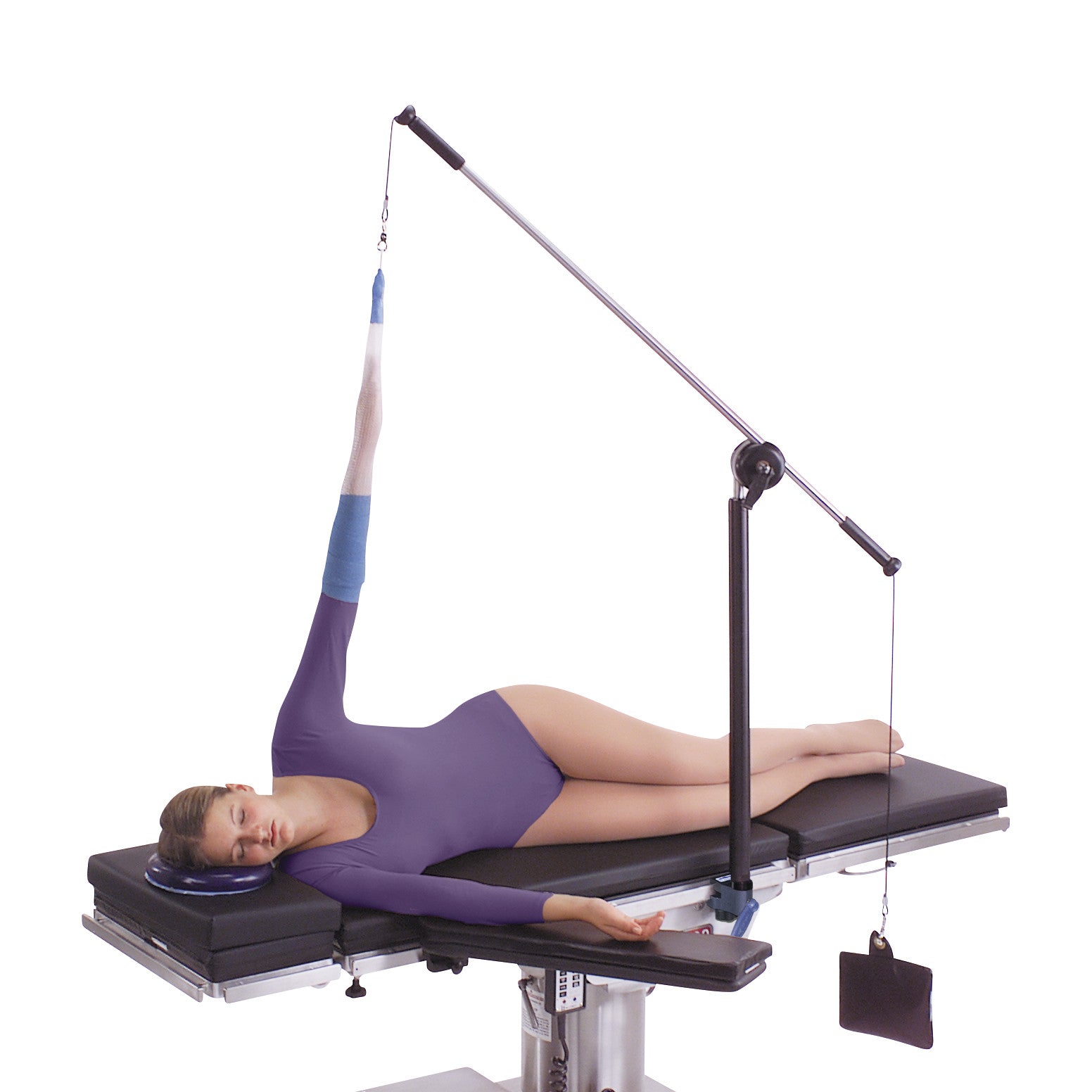 A person lies on a table with their arm secured in an elevated position using the Allen Arm Traction Device wearing a purple outfit.