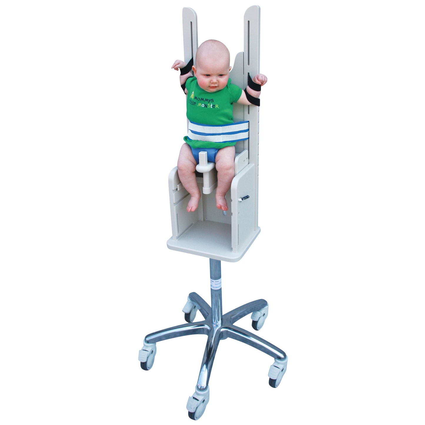 A baby is secured in a Pedia Poser, a medical imaging chair with straps and a metal base with wheels, designed for stability.