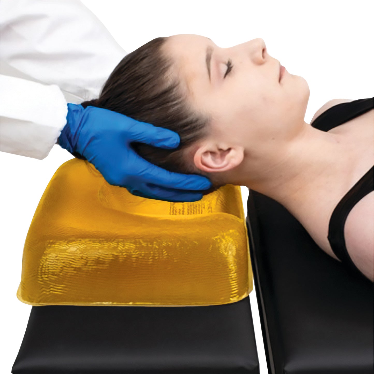 A person rests on an AliMed AliGel Ophthalmic Headrest. A gloved hand supports the head, which is on a textured, yellow cushion.