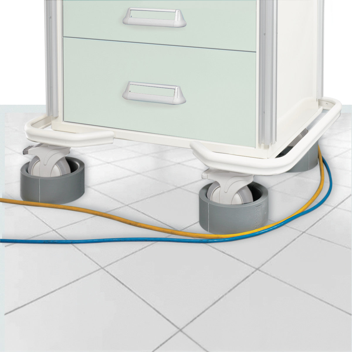 A medical cart with wheels is shown, equipped with AliMed Caster Guards, protecting cables on a tiled floor.