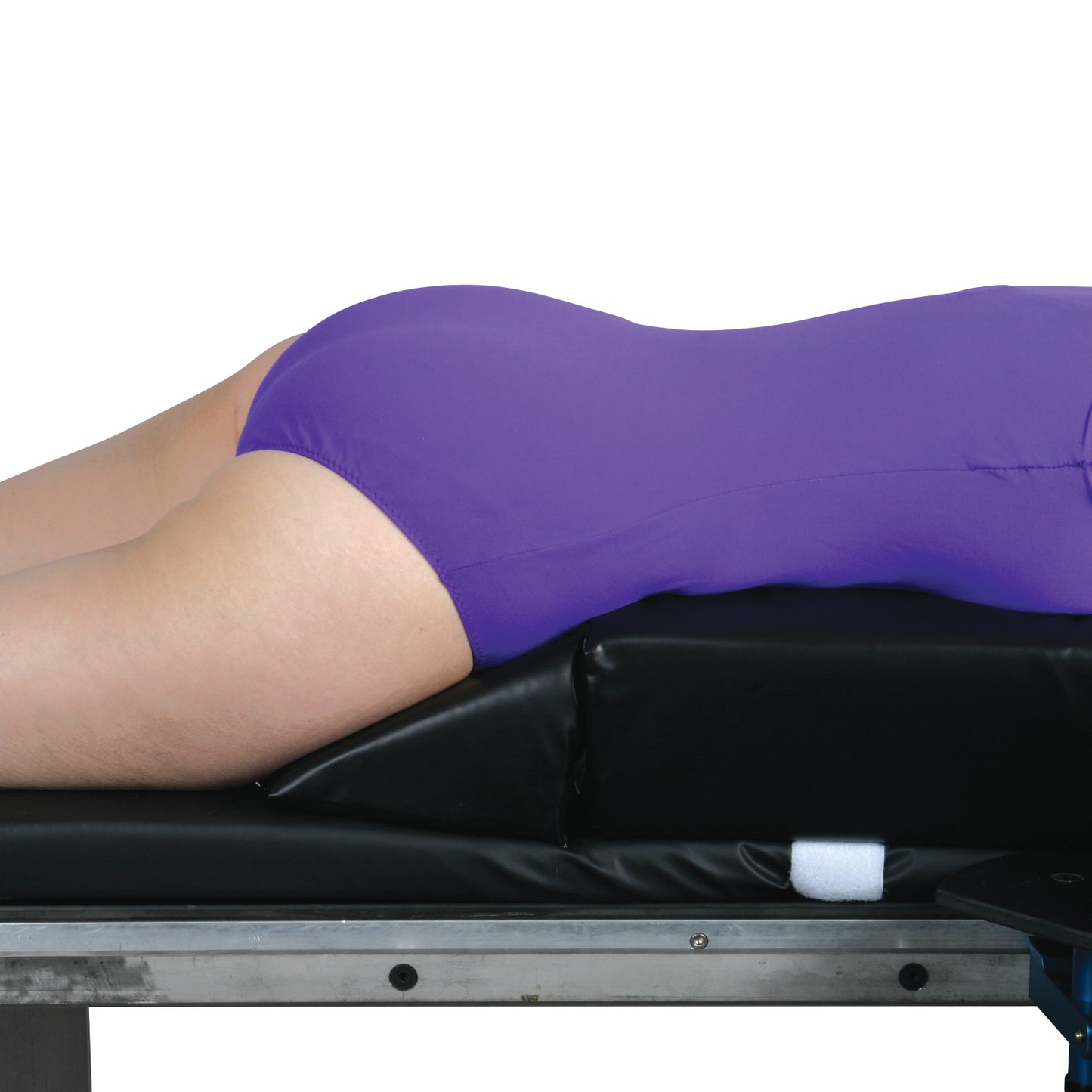 A person lies face down on the AliMed Vinyl-Covered Prone Lying System, which features a purple cover on a black cushion.