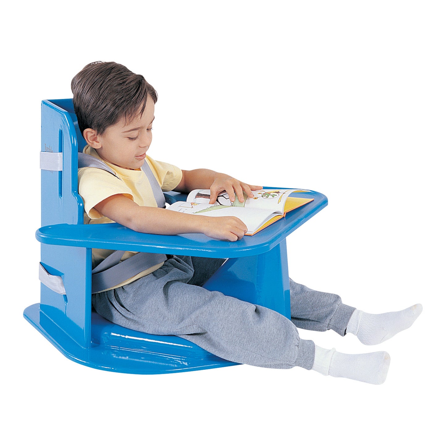 A child sits reading in a Tumble Forms2 Universal Corner Chair, a blue adaptive chair with a built-in tray and supportive straps.
