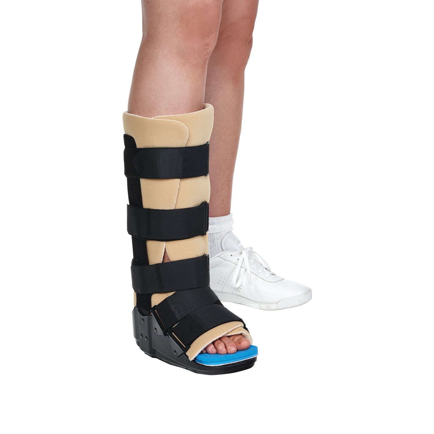 A person wears the AliMed Achilles Tendon Walker boot, featuring beige padding and black straps, next to a white sneaker.