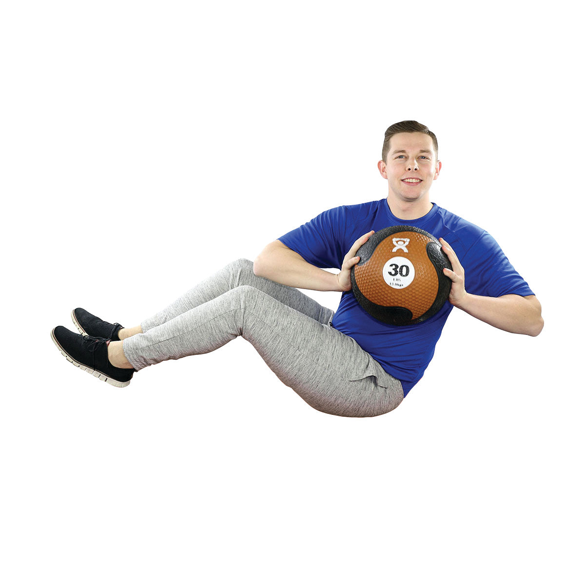 A person in a seated twist pose holds a 30 lb CanDo Rubber Medicine Ball, wearing a blue shirt, gray pants, and black shoes.