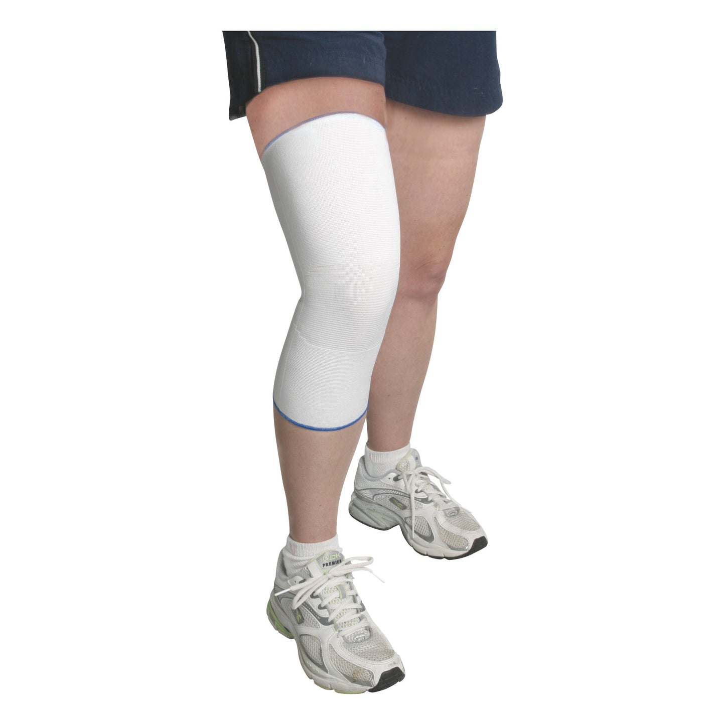 A person wearing shorts and white sneakers has an AliMed Seamless Knee Sleeve on their left leg, providing support and compression.