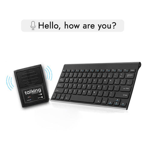 A black Talking Keyboard with large white keys, paired with a TextSpeak device. A hand points at the TextSpeak unit.