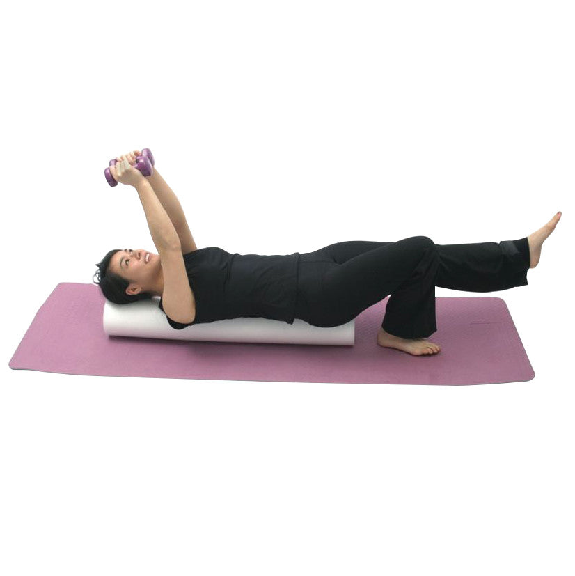 A woman exercises on a purple mat using the AliMed Foam Roller, holding small purple dumbbells and extending one leg.