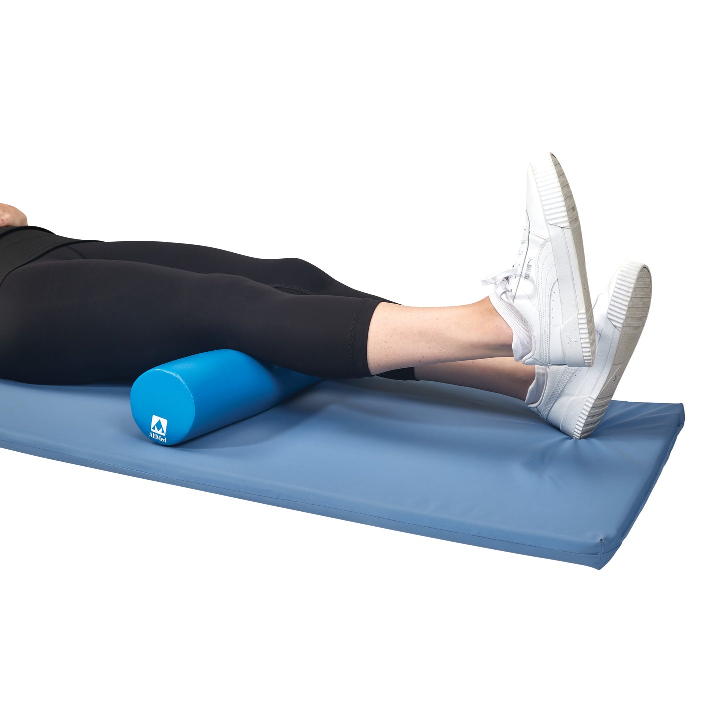 Person using the AliMed Antimicrobial-Treated Therapy Positioning Wedge under their legs on a blue mat, wearing white sneakers.