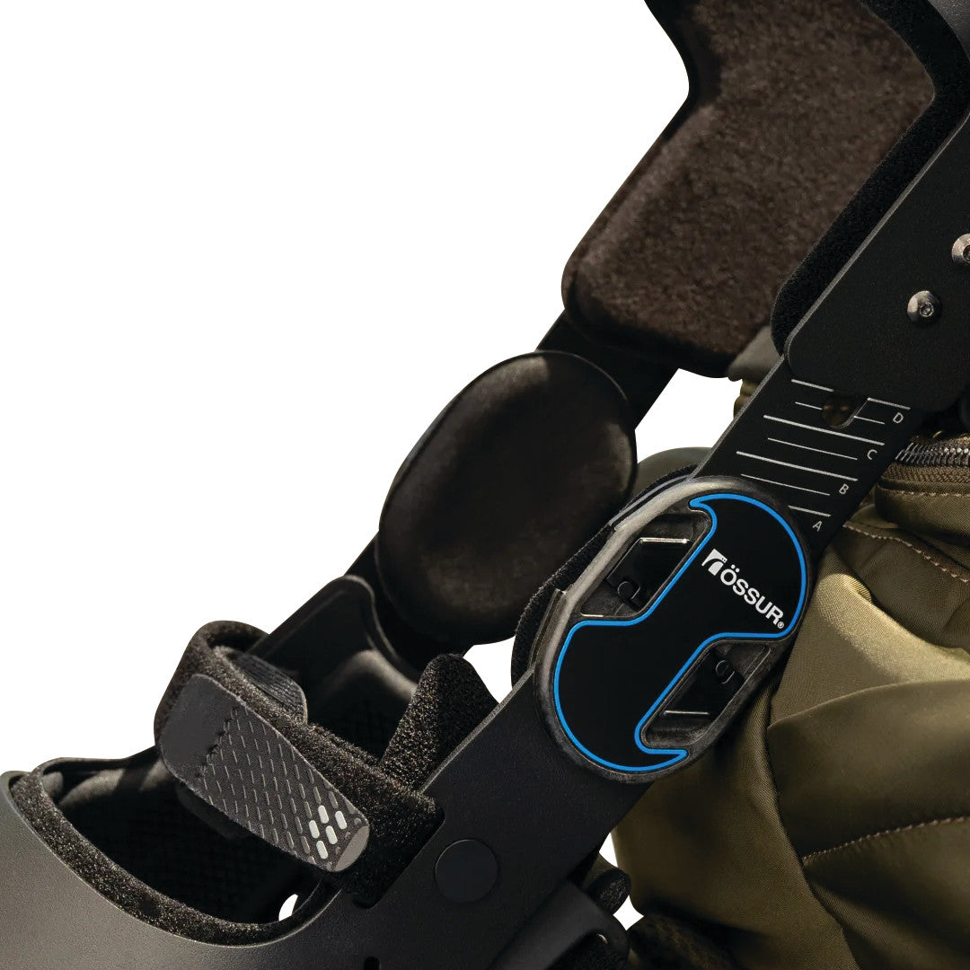 Close-up of the Ossur Rebound DUAL Knee Brace, showing adjustment dials and straps on a padded support structure.