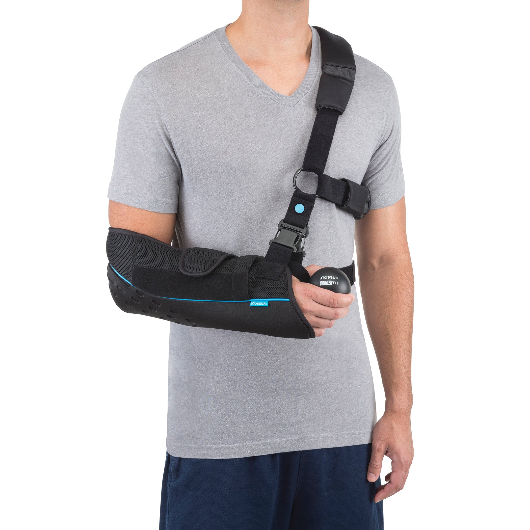 A person wears an Ossur Formfit Shoulder Brace over a gray T-shirt, supporting their left arm with adjustable straps.