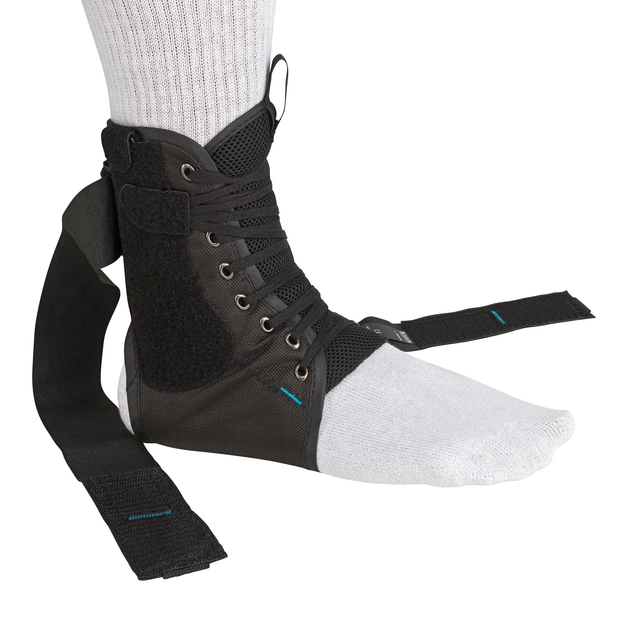 A person wears an Ossur Formfit Ankle Brace with Speedlace over a white sock. The brace is black with laces and straps.