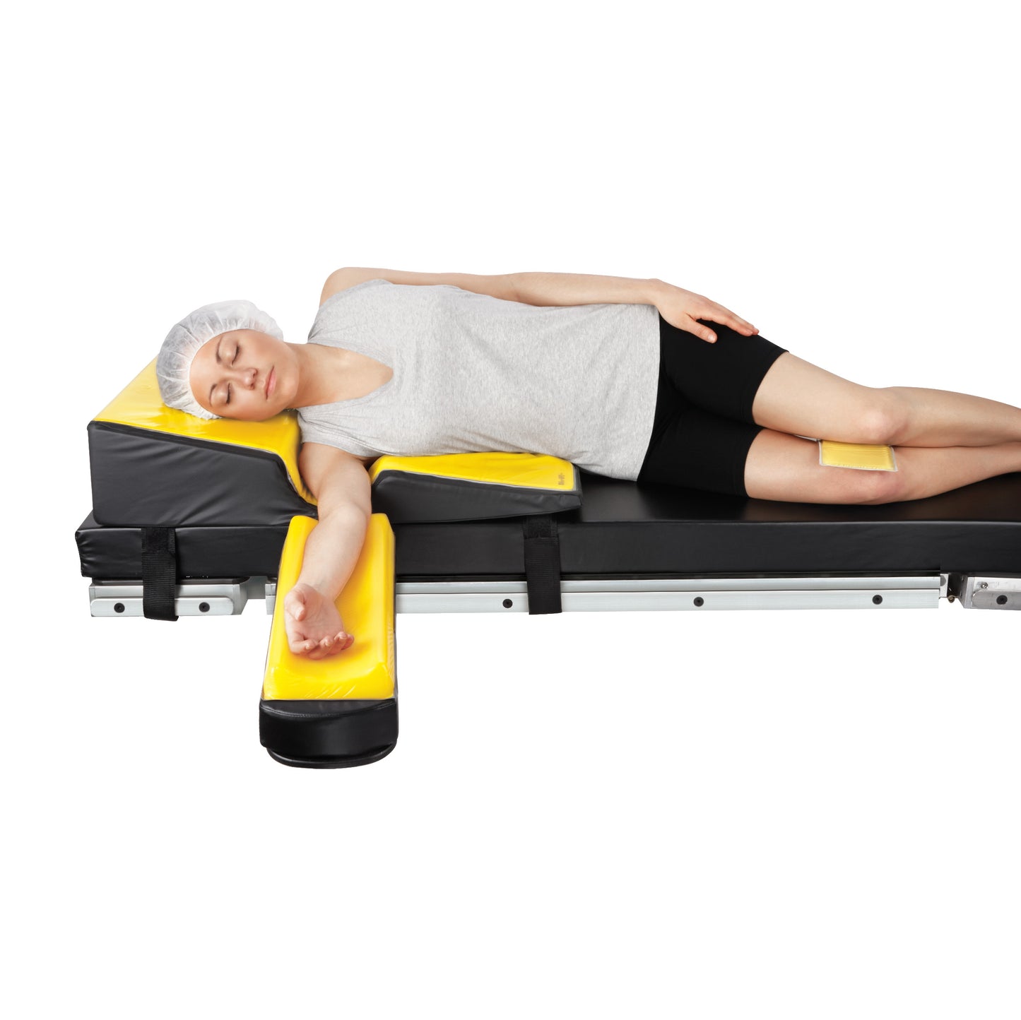 A person lies on the AliMed AliLite Lateral Positioner, a padded support system designed for side positioning on a flat surface.