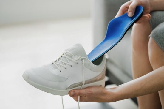 person inserting shoe insole into shoe