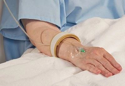 person with safety strap around iv in arm