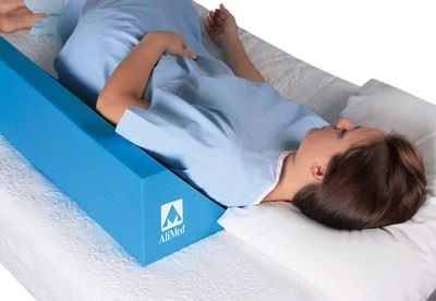 patient lying in bed with bed positioning wedge