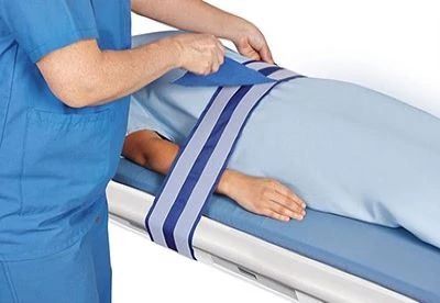 nurse putting patient safety strap on patient on operating table