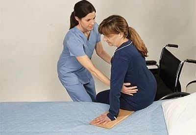 nurse helping patient on bed from wheelchair