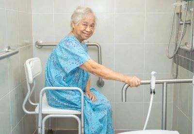 woman using rail and sitting on chair for aid in shower