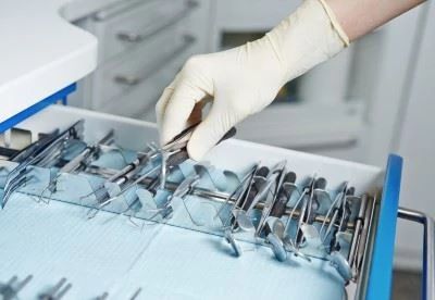 person picing up surgical curette