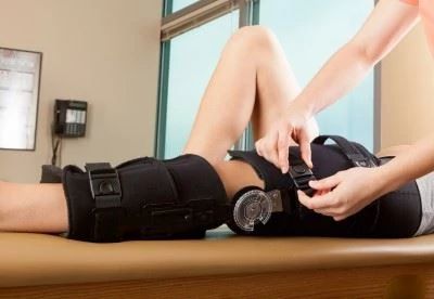 nurse putting acl knee brace on patient