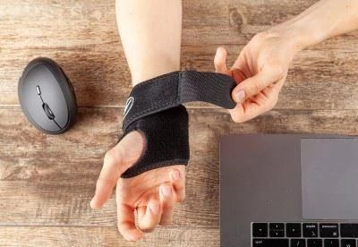 person putting on hand brace at desk