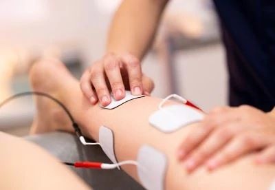 nurse putting electrodes on patients leg