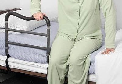 person using bed rail to get out of bed