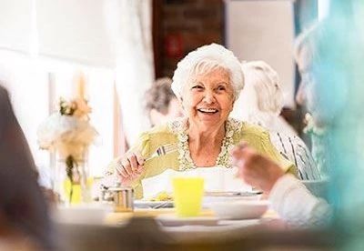 woman laughing at table while eating