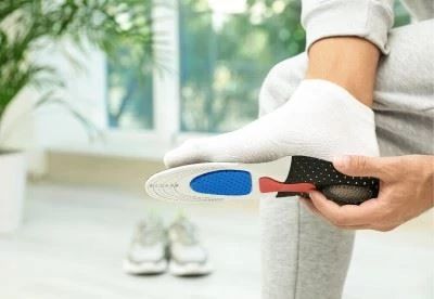 person holding arch support insole up to foot