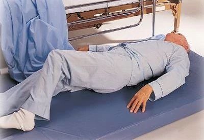 patient lying on fall mat next to bed
