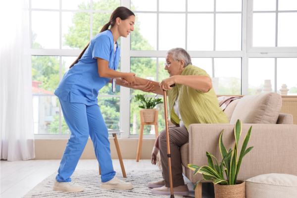 nurse helping man out of couch with a cane