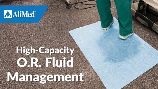 Operating room with person in scrubs standing on absorbent mat. Text reads "High-Capacity O.R. Fluid Management"