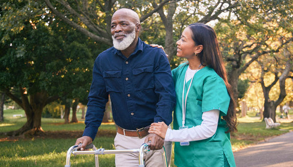 nurse helping man walk with walker