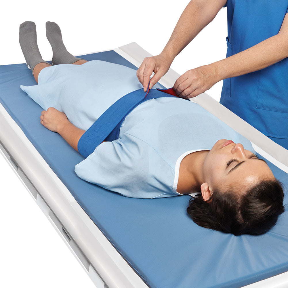 patient on table with imaging table pad with nurse putting imaging strap on patient