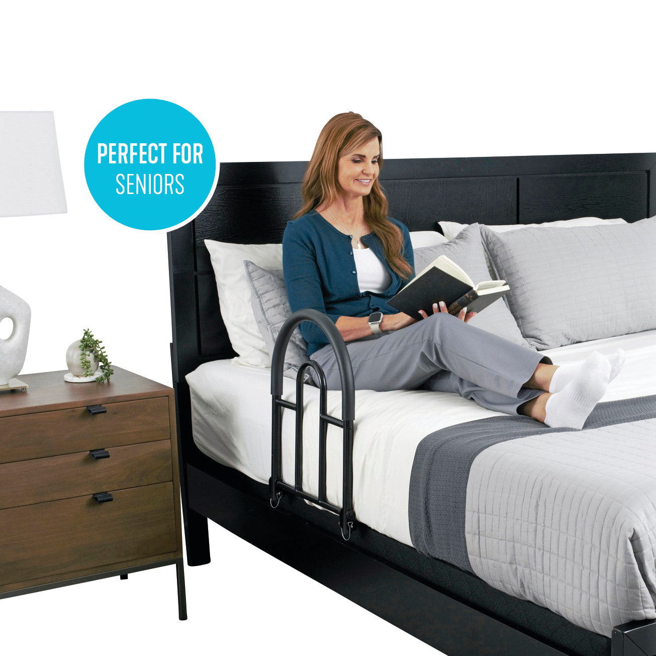A woman reads on a bed using the Bed Rail Advantage Traveler for support, described as 'Perfect for Seniors' in a nearby text.