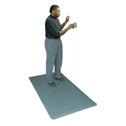 A person stands on a large, gray Wearwell ESD Anti-Fatigue Mat, reading a small tablet. The mat is designed to reduce fatigue.
