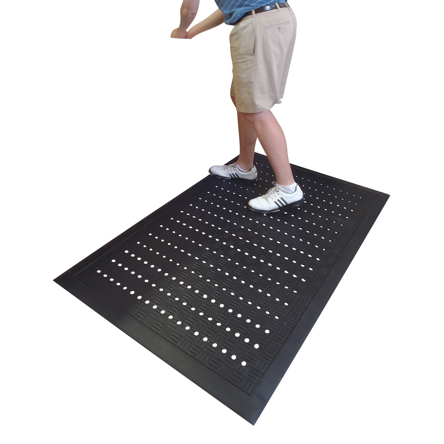 A person stands on a Cushion Station Anti-Fatigue Mat with perforated holes, wearing shorts and athletic shoes.