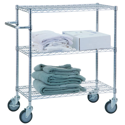 A 3-Shelf Chrome Utility Cart with wheels holds towels on the lower shelves and a white box with more towels on the top shelf.