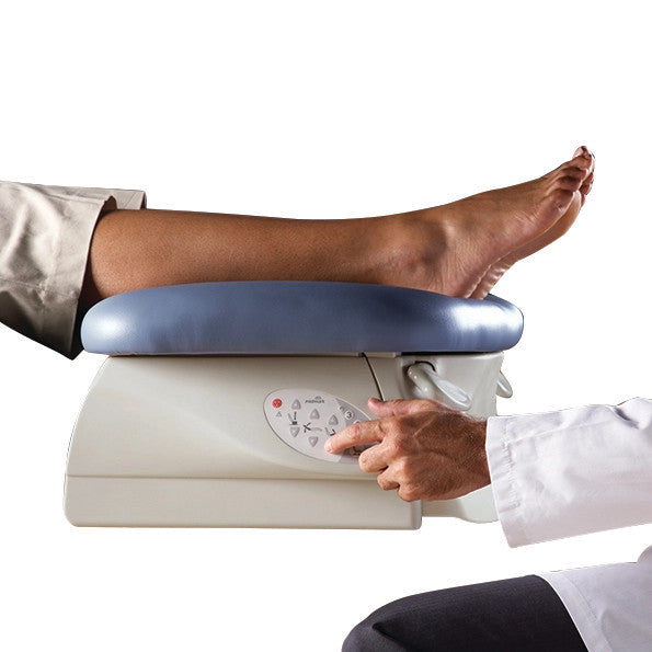 A leg rests on the Midmark Podiatry Chair Programmable Model 647 in blue. A person in a lab coat adjusts the chair's settings.