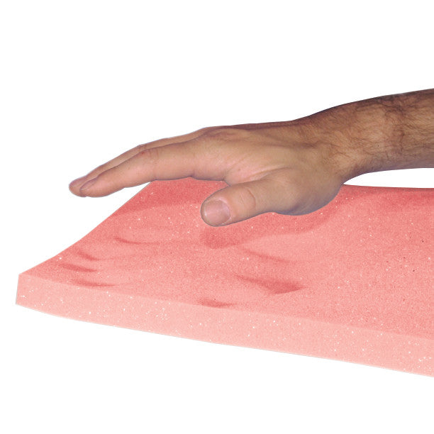 A hand presses on the AliMed T-Foam Uncovered Wheelchair Cushion, showing its pink foam with visible hand impressions.