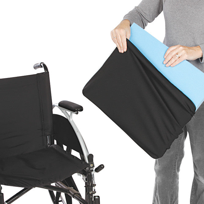 A person holds an AliMed Replacement Wheelchair Cushion Cover with a light blue cushion inside, near a black wheelchair.