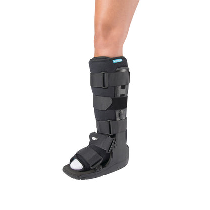 A person wearing an Ossur Formfit High-Top Walker boot. It is black with adjustable straps and covers the lower leg.