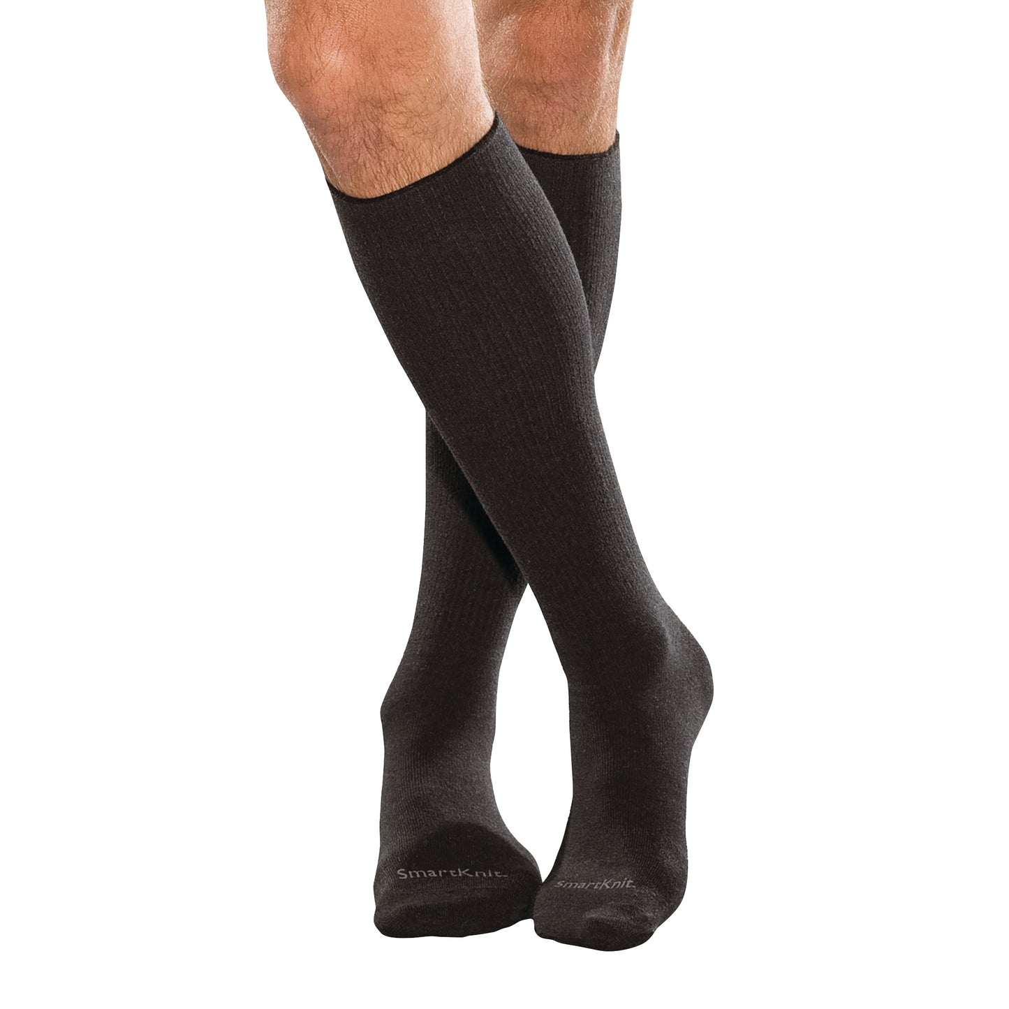 A person wearing black SmartKnit Seamless Over-the-Calf Socks, standing with legs crossed, showing the socks' knee-high length.
