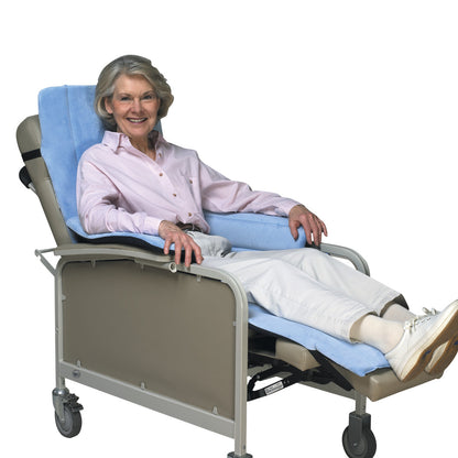 A woman sits in a reclined SkiL-Care Geri-Chair Cozy Seat with light blue padding and gray frame, looking comfortable and relaxed.