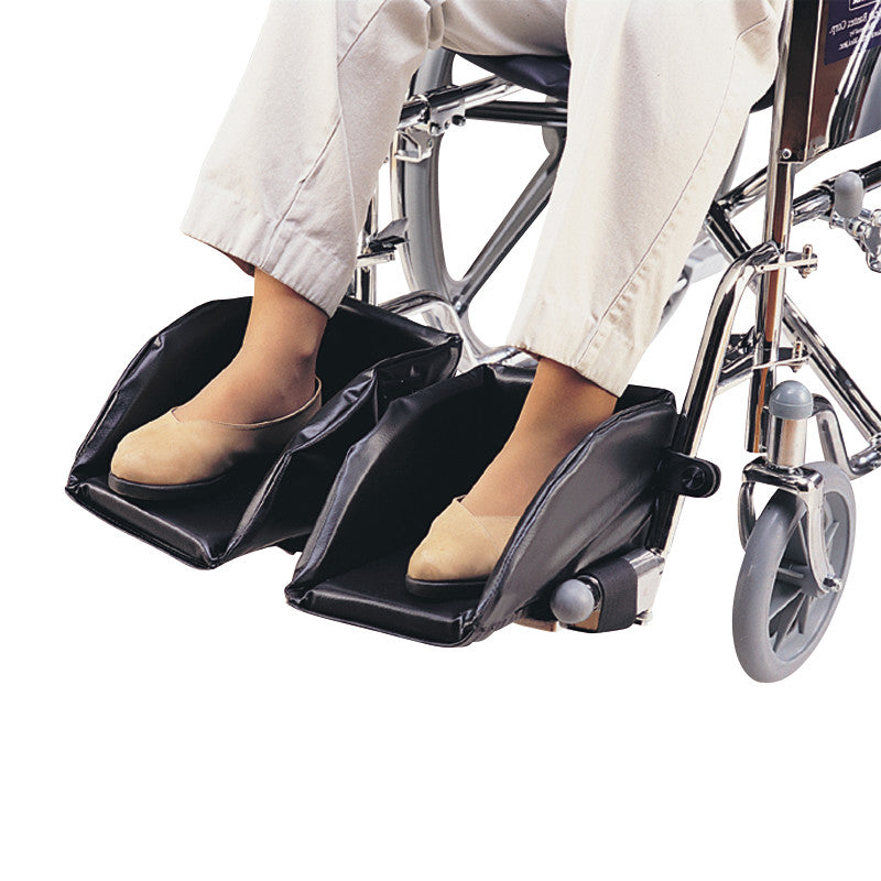 Woman's feet rest in SkiL-Care Swing-Away Foot Support on a wheelchair, offering padded, adjustable foot positioning.