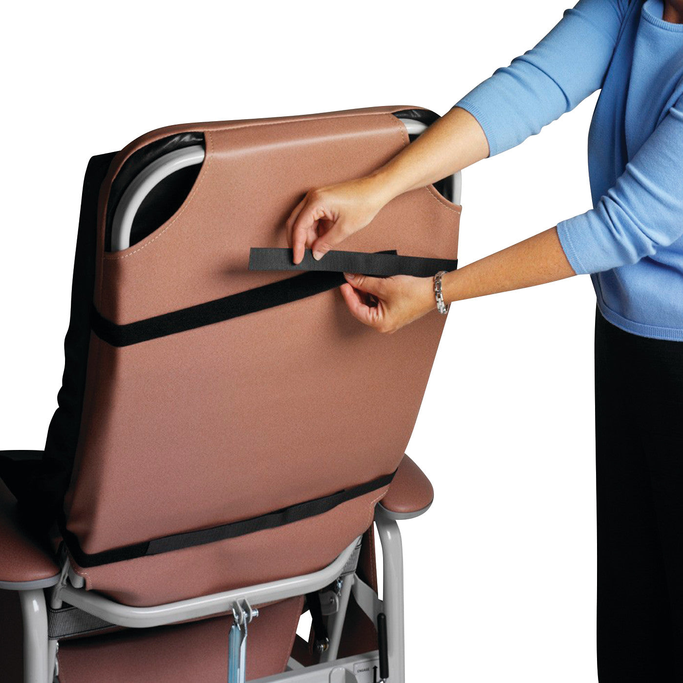 A person adjusts a strap on the back of a brown Geo-Wave Specialty Recliner Cushion attached to a recliner.