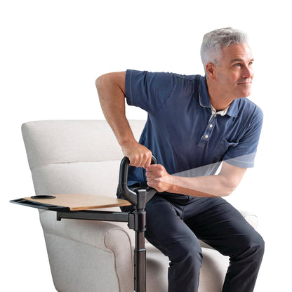 A person uses the Assist-A-Tray, a support handle with an attached tray, while getting up from a chair.