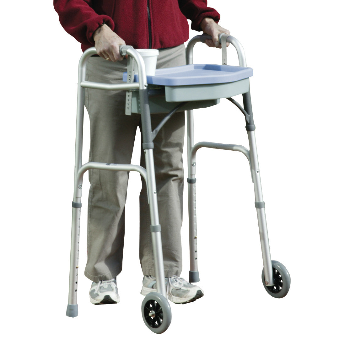 A person uses a walker with the Drive Medical E-Z Walker Caddy. The caddy holds a cup and has a tray on the front.