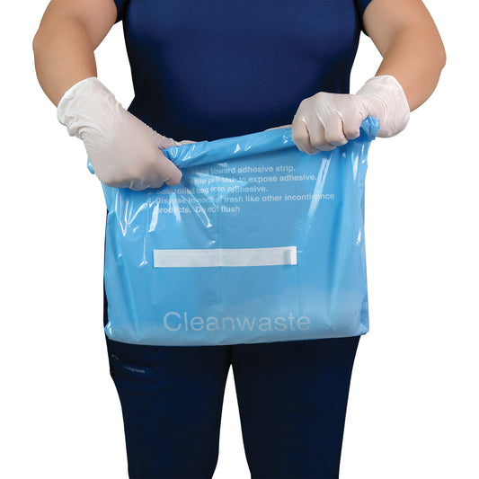 Person wearing gloves holds a blue bag labeled "Cleanwaste." It's THE SANI-BAG+ Commode Liner with adhesive instructions visible.